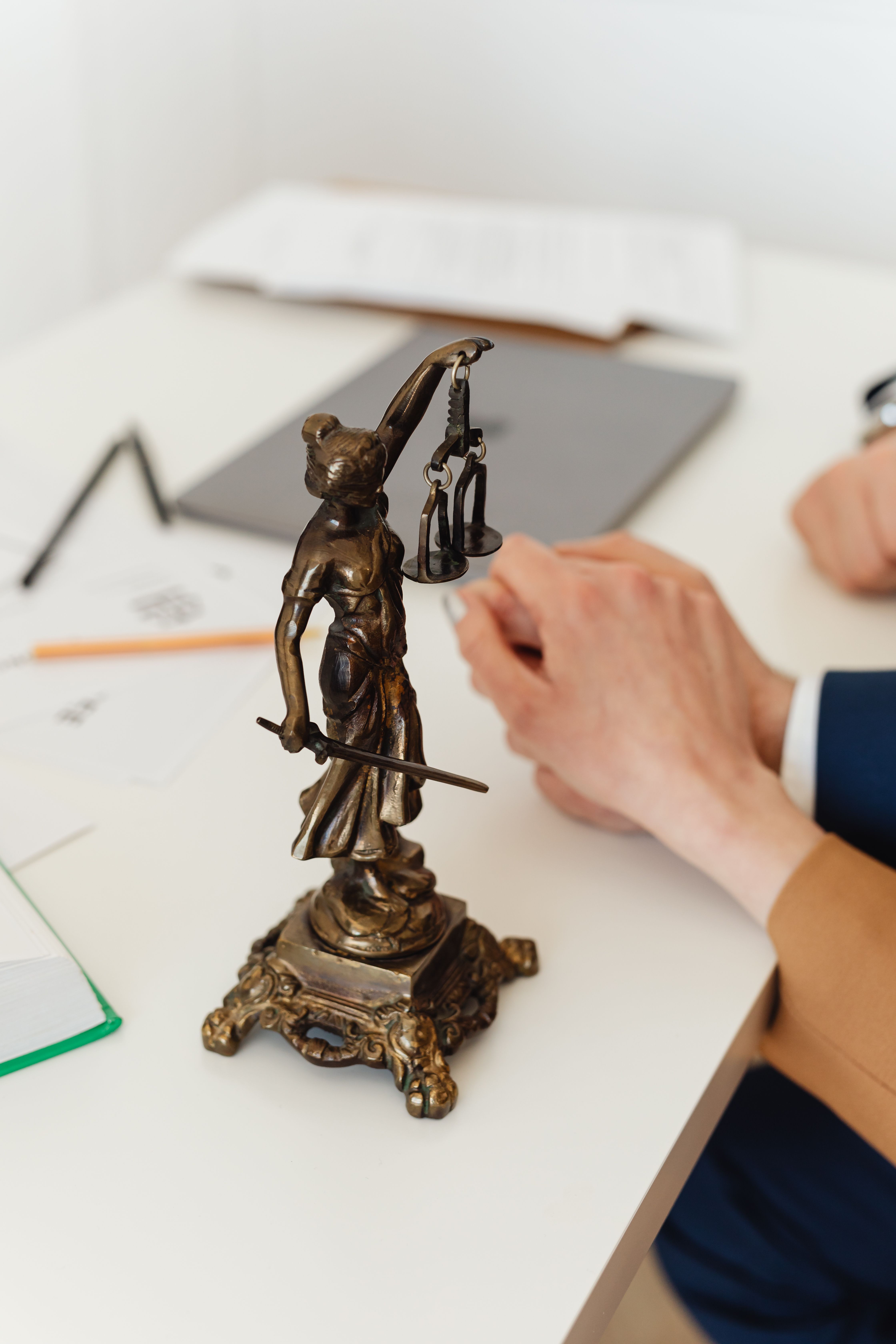 Estatueta da deusa da Justiça sobre mesa de trabalho em escritório de advocacia
